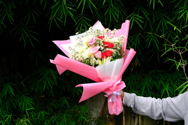 uma mão segurando um buquê de rosas e crisântemos. romântico. florais. flores.