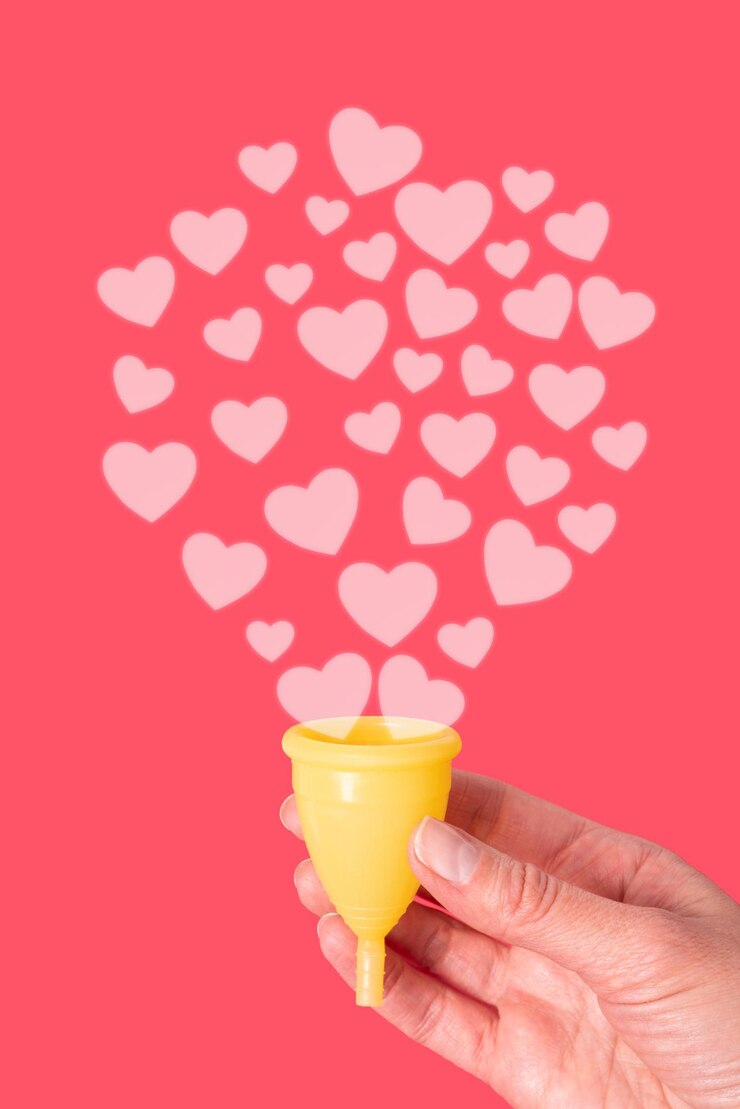 Foto uma mão segurando um copo menstrual amarelo em um fundo vermelho com corações rosa como gotas menstruais conceito de saúde da mulher conceito ecológico conceito de desperdício zero