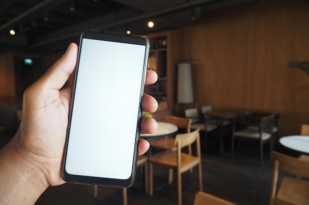 Uma mão segurando um smartphone em um café de moda irradiando uma atmosfera contemporânea