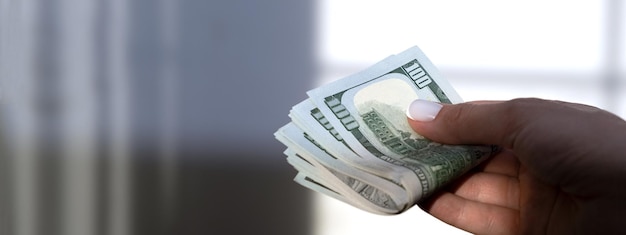 Foto uma mão segurando uma pilha de notas de 100 dólares