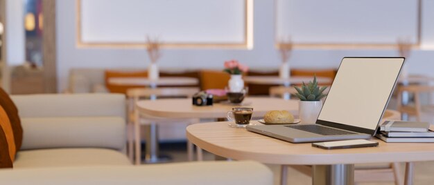 Uma maquete de computador portátil com café e acessórios em uma mesa de café em um espaço de trabalho co moderno