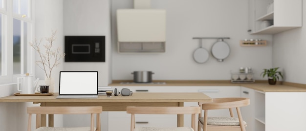 Uma maquete de laptop em uma mesa de jantar de madeira na cozinha branca contemporânea moderna