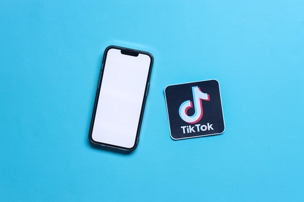 Uma maquete de smartphone de tela em branco com papel impresso do logotipo do aplicativo de mídia social chamado Tiktok