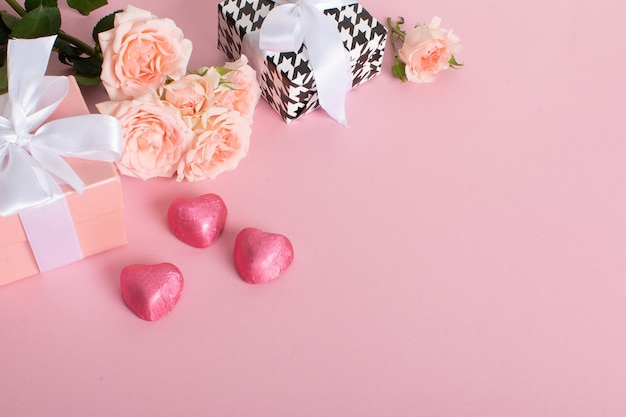 Uma maquete de um banner do Dia dos Namorados com uma caixa de presente doces em forma de coração e um buquê de rosas em um fundo rosa