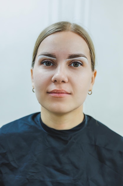 Uma maquiadora permanente desenha um esboço das sobrancelhas no rosto de seu cliente