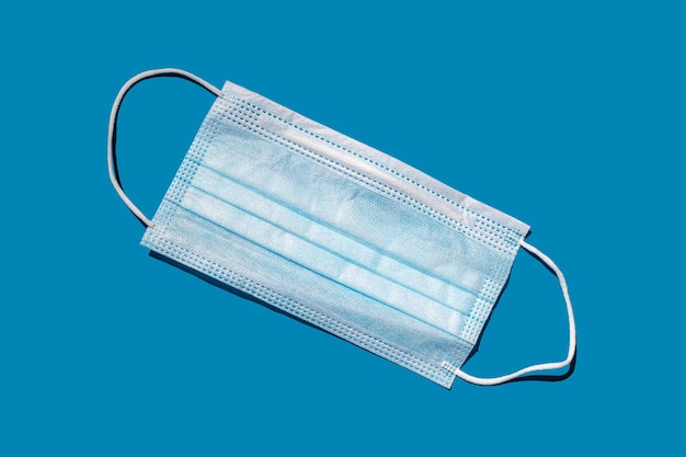Uma máscara facial descartável de fundo sólido azul proteção contra COVID-19 visão de alto ângulo