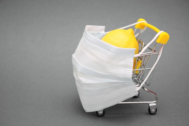 Foto uma máscara médica é colocada em um carrinho de compras contendo um limão fresco.