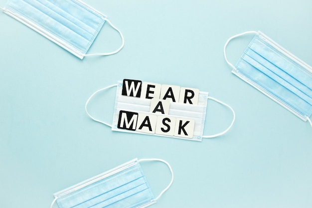 Uma máscara médica e uma mensagem de texto são colocadas em uma máscara sobre um fundo azul claro. Cartaz, proteção de vírus de banner. Um espaço vazio.