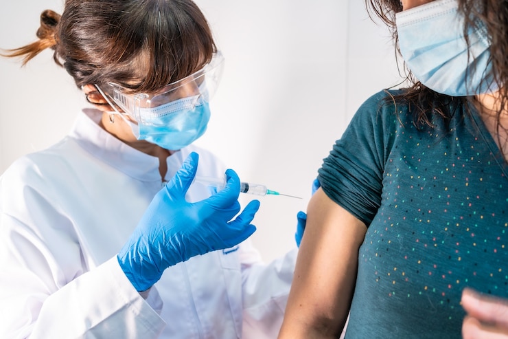 Foto uma médica com máscara facial aplicando a vacina contra o coronavírus, a paciente com medo da vacina e seus efeitos colaterais.