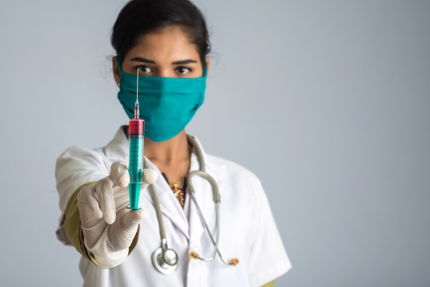 Uma médica com um estetoscópio está segurando e mostrando uma injeção ou seringa.