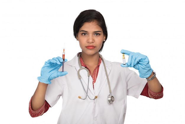 Uma médica com um estetoscópio está segurando uma injeção ou seringa.