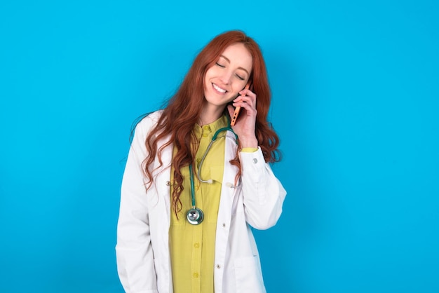Uma médica engraçada ri alegremente tem uma conversa telefônica sendo divertida por um amigo fecha os olhos