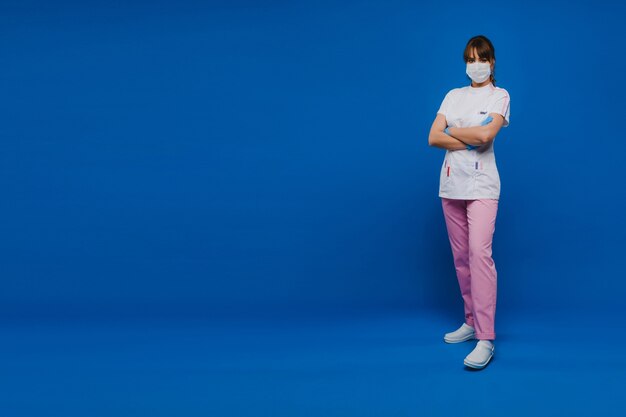 Uma médica está com uma máscara médica, isolada em um fundo azul. Uma enfermeira com roupas brancas sobre um fundo azul