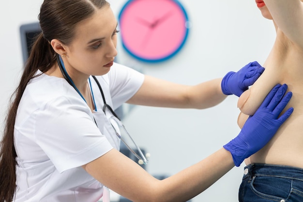 Foto uma médica examina o peito de uma jovem paciente, pressionando suavemente com as mãos