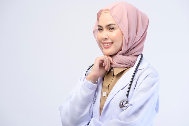 Uma médica muçulmana com hijab sobre estúdio de fundo branco.