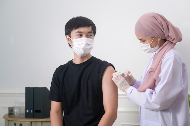 Uma médica muçulmana injetando vacina covid-19 no braço do paciente, vacinação covid-19 e conceito de saúde