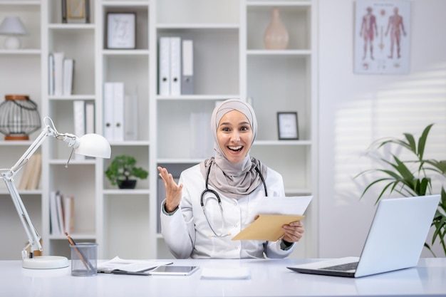 Uma médica muçulmana profissional usando um hijab irradia positividade enquanto consulta com