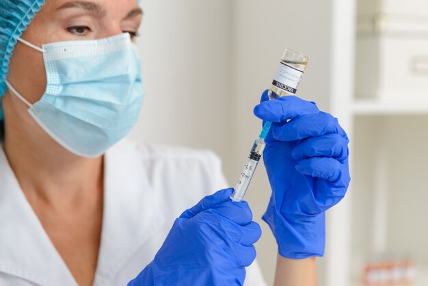 Uma médica ou enfermeira enche uma seringa com o close da vacina contra o coronavírus Covid19