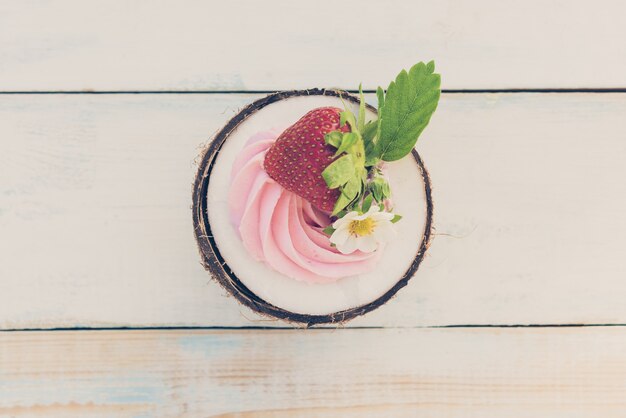 Uma meia rodada de coco com morangos e cream cheese em uma mesa de madeira. conceito de comida saudável. imagem tonificada, vista superior