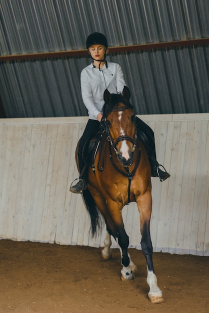 Uma menina a cavalo montando uma arena