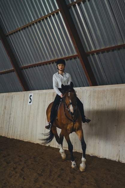 Uma menina a cavalo montando uma arena