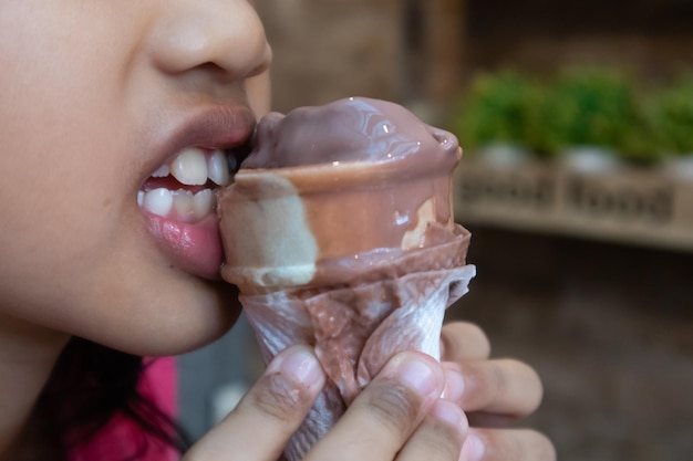 Uma menina a comer um gelado de chocolate