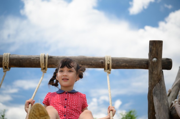 Uma menina a divertir-se num baloiço num dia claro