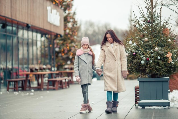 Uma menina adorável com a mãe a patinar na pista de gelo.