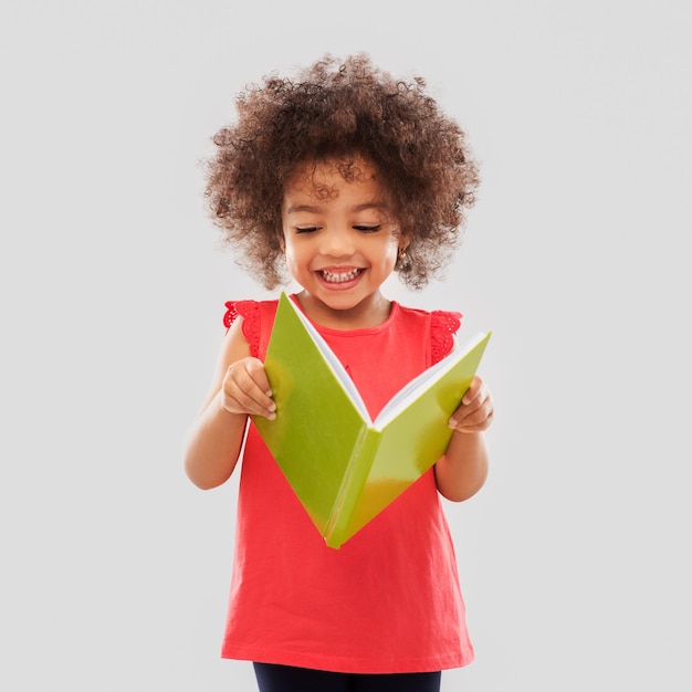 Foto uma menina afro-americana feliz a ler um livro.