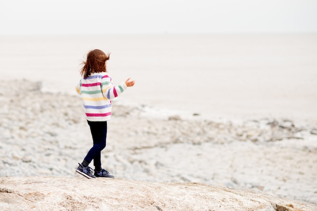 Uma menina andando e brincando à beira-mar