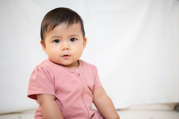 Uma menina asiática de cerca de 1 ano brincando na sala de estar da casa Um bebê fofo vestindo um vestido rosa Fique com os pais em casa