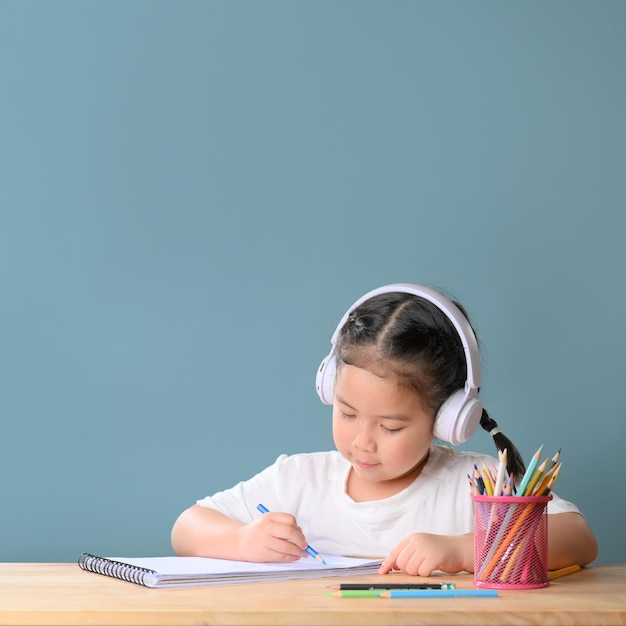 Uma menina asiática feliz estudando aula de aprendizagem on-line com o professor de zoom de videochamada on-line em casa. E-learning ou conceito de educação escolar em casa. Novo coronavírus normal.Covid-19. Distanciamento social.