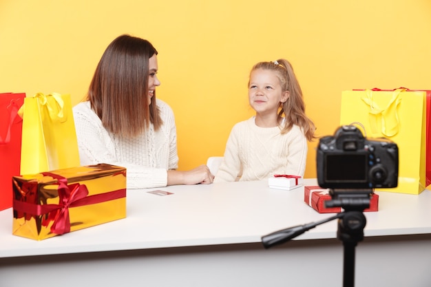 Uma menina blogueira sentada com a mãe e gravando um vlog juntas.