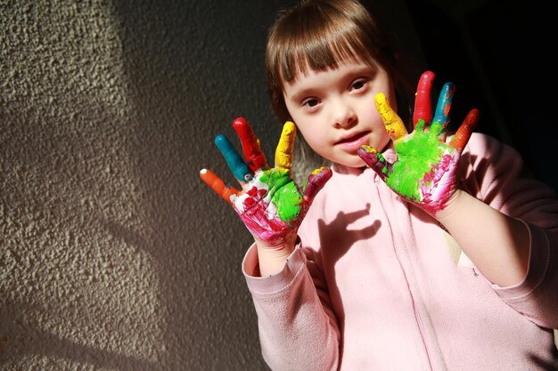 Foto uma menina bonita com as mãos pintadas.