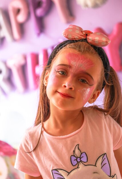 uma menina bonita com cabelos castanhos e olhos verdes claros, feliz e sorridente, jogando em seu aniversário