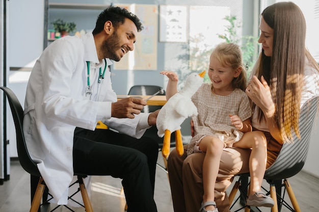 Uma menina bonita com sua mãe está sendo examinada por um pediatra no hospital