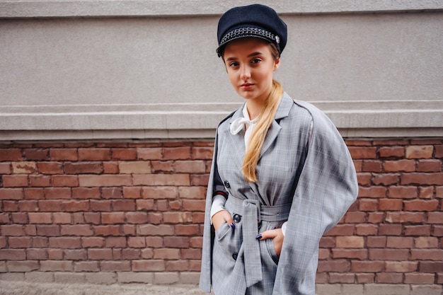 Uma menina bonita e bonita em um elegante terno anda pela cidade e poses