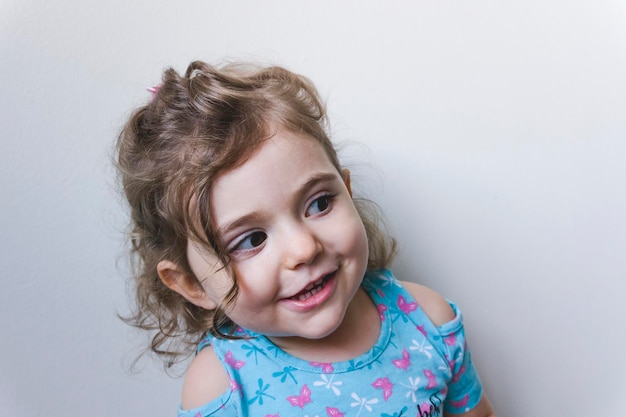 Uma menina bonita e sorridente de pé contra um fundo branco