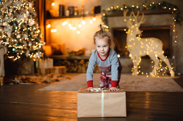 Uma menina bonita em pijama tradicional recebeu um presente de Natal