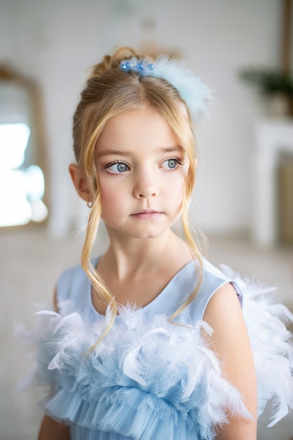 Foto uma menina bonita em um vestido azul maquiagem infantil e penteado para uma princesinha, enfeites de cabelo