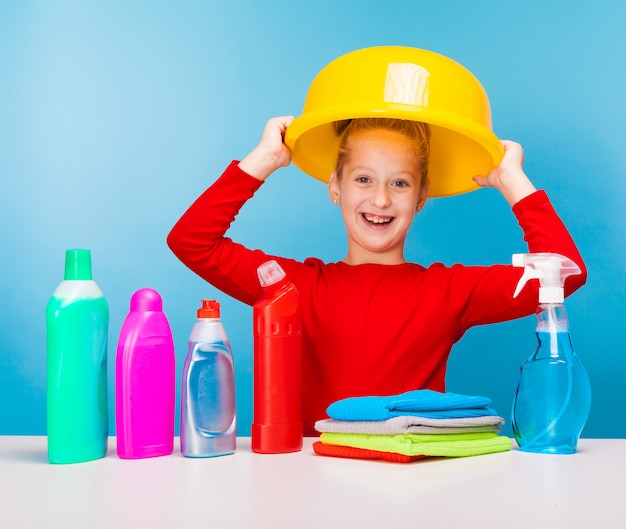 Uma menina bonita segurando produtos de limpeza, fazendo trabalhos domésticos