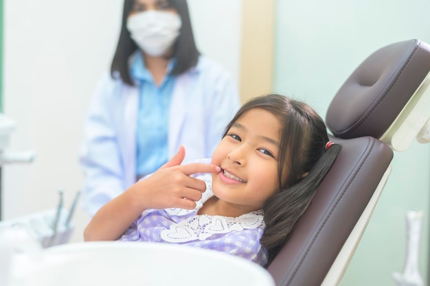 Uma menina bonita tendo os dentes examinados pelo dentista na clínica odontológica