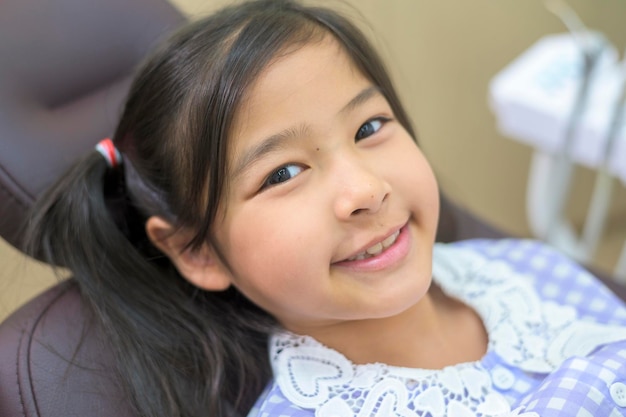 Uma menina bonita tendo os dentes examinados pelo dentista na clínica odontológica