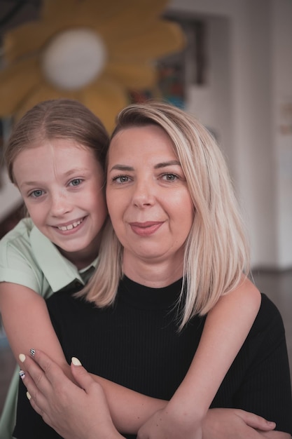 Uma menina bonitinha beija e abraça sua mãe na pré-escola