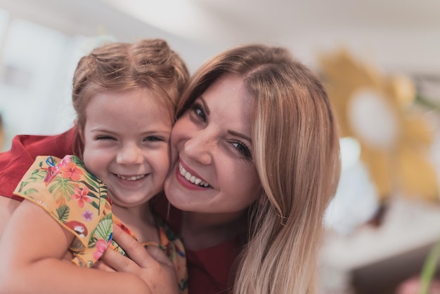 Uma menina bonitinha beija e abraça sua mãe na pré-escola