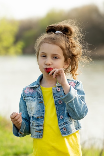 Uma menina bonitinha come morangos. Piquenique. Primavera. Delicioso. Férias com a família.