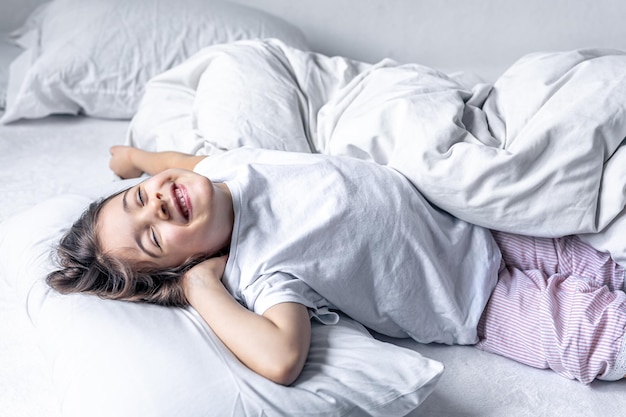 Uma menina bonitinha deita na cama e não quer se levantar