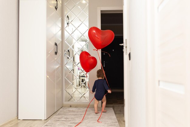 Uma menina bonitinha está brincando com uma bola vermelha em forma de coração Lindo cartão postal de presente