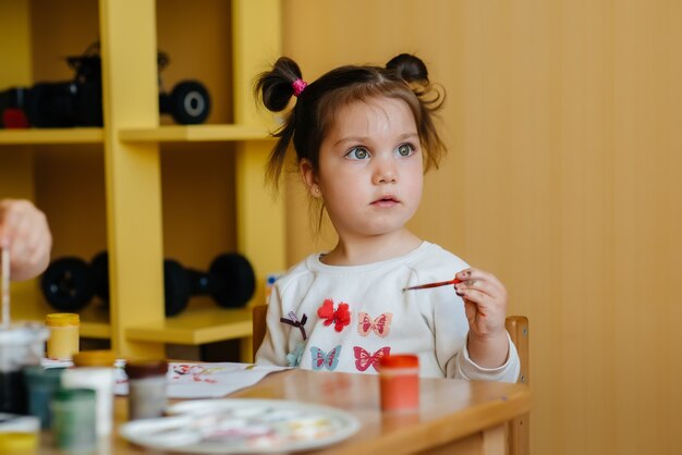 Uma menina bonitinha está brincando e pintando no quarto dela. Recreação e entretenimento.