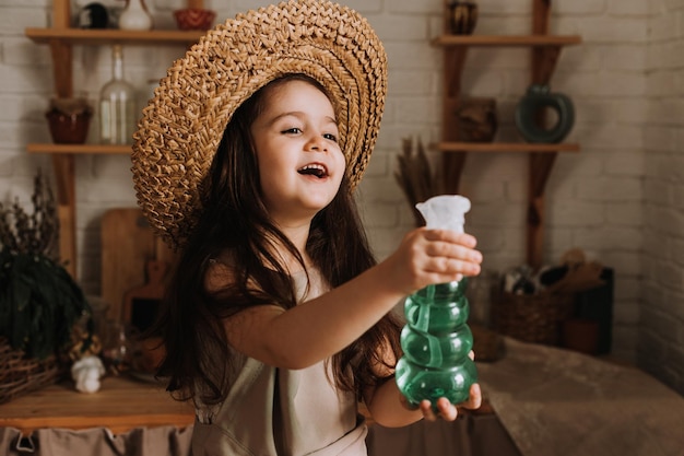 Uma menina bonitinha planta e rega uma flor em um vaso em casa Um pequeno morador de verão cuida das flores da casa Dia da Terra